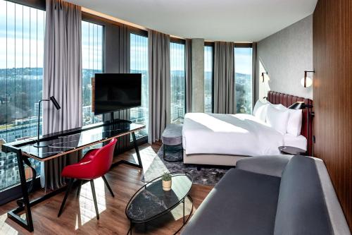 a hotel room with a bed and a desk at Radisson Blu Hotel at Porsche Design Tower Stuttgart in Stuttgart