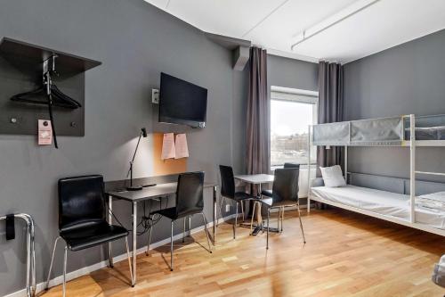 1 dormitorio con litera, escritorio y sillas en Aiden by Best Western Stockholm Kista en Estocolmo