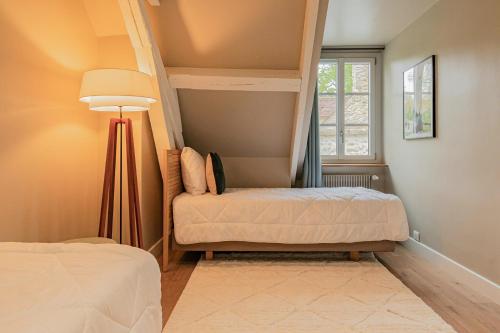 a bedroom with two beds and a lamp and a window at Le Moulin de l'Ortille & SPA in Compiègne
