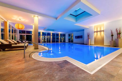 a large swimming pool in a hotel room with a large at Vitalpina Hotel Waldhof in Rablà