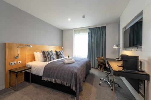 a hotel room with a bed and a desk and a television at Apex City of Edinburgh Hotel in Edinburgh