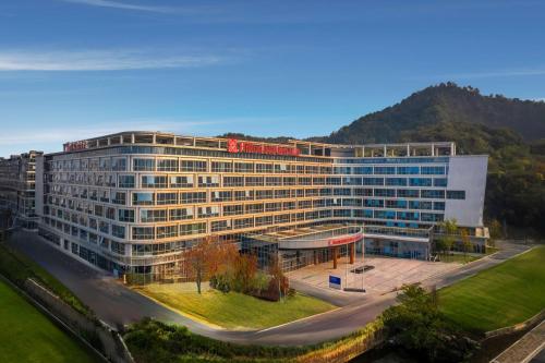 a large building with a red sign on top of it at Hilton Garden Inn Huzhou High-Speed Railway Station in Huzhou