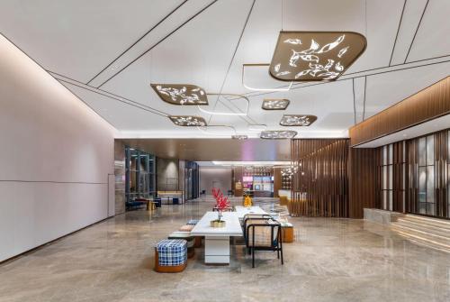 a lobby with tables and chairs in a building at Hilton Garden Inn Huzhou High-Speed Railway Station in Huzhou
