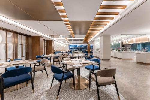 a restaurant with tables and chairs and a kitchen at Hilton Garden Inn Huzhou High-Speed Railway Station in Huzhou