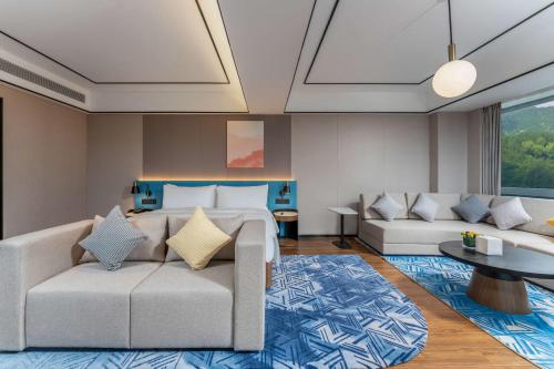 a living room with two couches and a bed at Hilton Garden Inn Huzhou High-Speed Railway Station in Huzhou