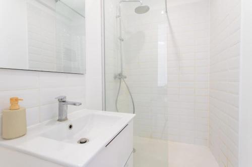 une salle de bain blanche avec un lavabo et une douche dans l'établissement Bel Appartement Cosy proche du métro - Lille, à Lille