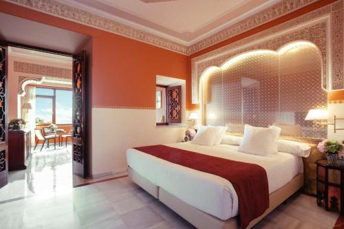 sypialnia z dużym łóżkiem z pomarańczowymi ścianami w obiekcie Alhambra Palace Hotel w Grenadzie