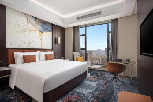 a bedroom with a large white bed and a large window at Wyndham Garden FuKang Downtown in Fukang
