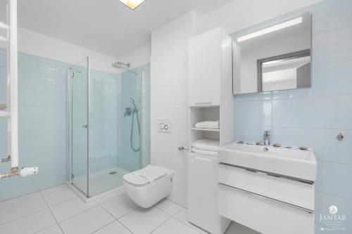 a white bathroom with a toilet and a shower at Jantar Apartamenty - 5 Mórz Sianożęty in Sianozety