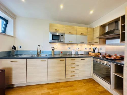 cocina grande con armarios de madera y fregadero en Stylish Zone 2 city Apartment, en Londres