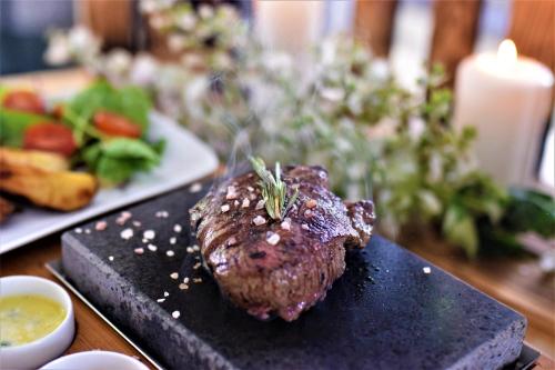 a piece of meat on a black plate on a table at Gościniec in Myszęcin