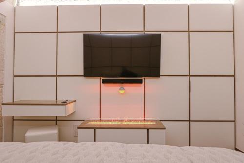 a room with a bed and a tv on a wall at Ulivi Bianchi Luxury Home in Puglia in Putignano