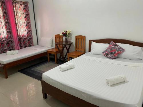 a bedroom with two beds and a table and chairs at TheSoftbed Homestay in San Vicente