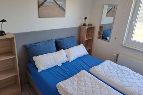 uma cama com lençóis azuis e almofadas brancas num quarto em Wijk de Brabander 134 em Cadzand