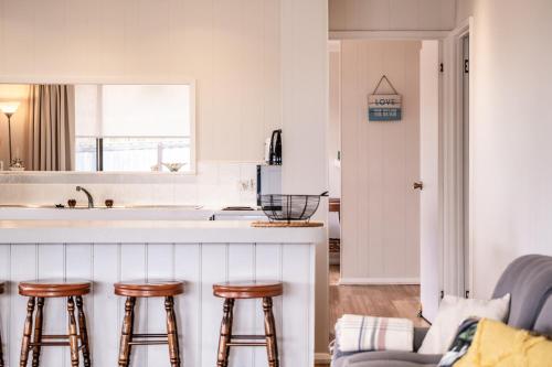 a kitchen with a counter and three bar stools at Stones Throw in Primrose Sands