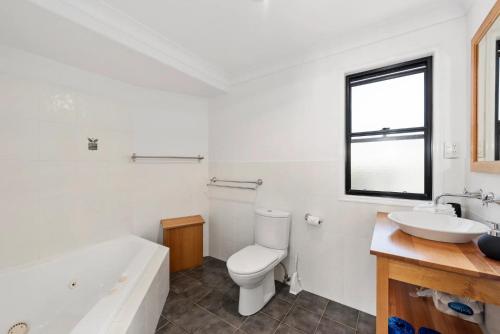 a bathroom with a tub and a toilet and a sink at Jetty Escape Townhouse in Coffs Harbour