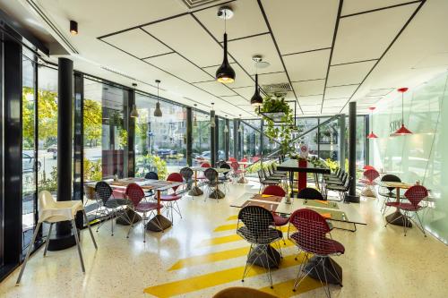 una habitación con mesas, sillas y ventanas en ibis Styles Bucharest Erbas, en Bucarest