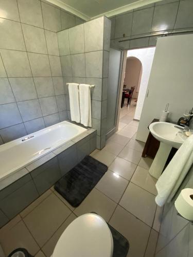 Un baño con bañera, inodoro y lavabo. en The Lake Villa, en Benoni