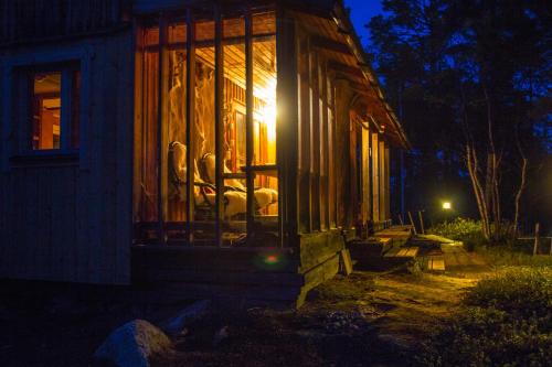 a house with a window on the side of it at night at Private Island VESI - The White Blue Wilderness Lodge in Inari