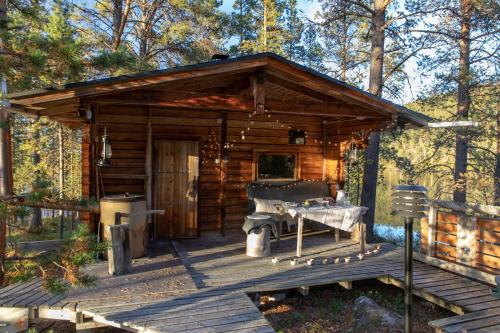 a wooden cabin with a table on a deck at Private Island VESI - The White Blue Wilderness Lodge in Inari