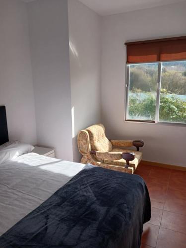 ein Schlafzimmer mit einem Bett und einem Stuhl und einem Fenster in der Unterkunft Alojamiento PLAYA DE PANTIN in Valdoviño