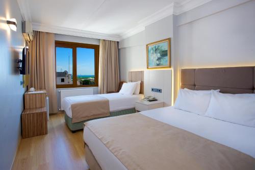 イスタンブールにあるグランド アント ホテルのベッド2台と窓が備わるホテルルームです。