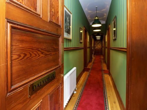 a hallway with green walls and a red carpet at Dalvorar - Mar Lodge Estate in Ballater