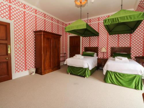 two beds in a room with red and white wallpaper at Dalvorar - Mar Lodge Estate in Ballater