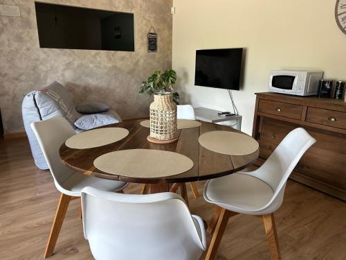 un salon avec une table en bois et des chaises blanches dans l'établissement Au cœur des bois, à Saint-Germain-du-Salembre