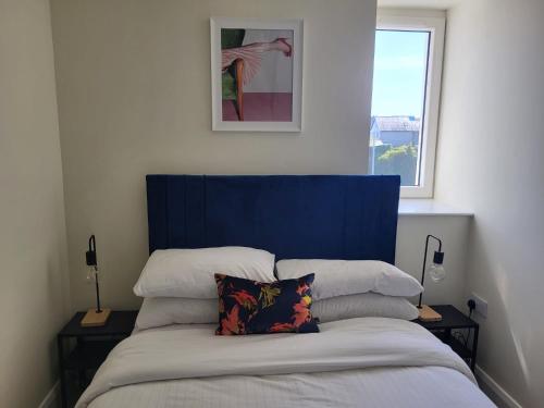 a bed with a blue headboard in a bedroom at 360 Town Stay Apartments & Studios in Dungarvan