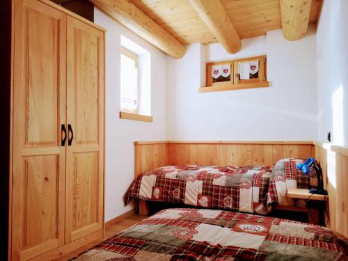 1 dormitorio con 2 camas, ventana y puerta en Baita Naibiz, en Palù del Fersina