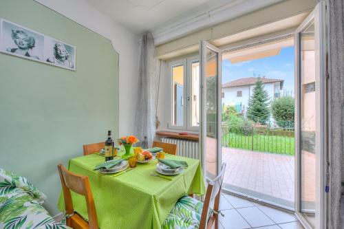 ein Esszimmer mit einem grünen Tisch und einem Balkon in der Unterkunft Leonardo House Garden Stresa Center - Happy Rentals in Stresa