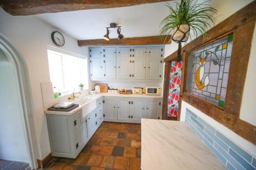 a kitchen with white cabinets and a window at Charming 2-Bed Cottage in Mickle Trafford- Sleeps 6 - Pet Friendly - Near Chester 