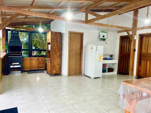 a kitchen with a white refrigerator and wooden ceilings at Suítes Recanto Monte trigo in São Francisco do Sul