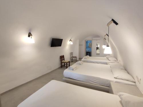 two beds in a room with white walls at Central Santorini Serenity Rooms in Fira