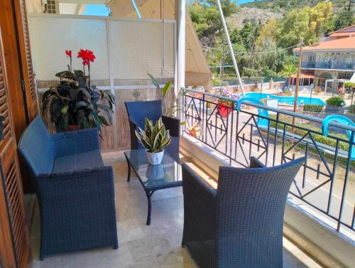 einen Balkon mit Stühlen, einem Tisch und einem Pool in der Unterkunft Helens Apartment in Tolo