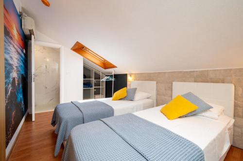 two beds in a hotel room with yellow and blue at Villa Jidro in Trogir