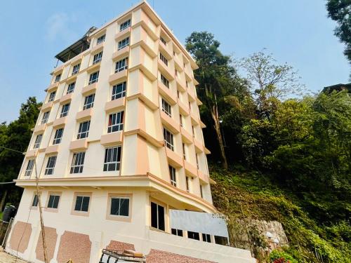 a tall white building with trees in the background at Staynest Regency Pelling in Pelling