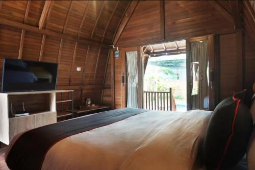 a bedroom with a large bed and a television at Nemuru Villa Ubud Anyer in Anyer