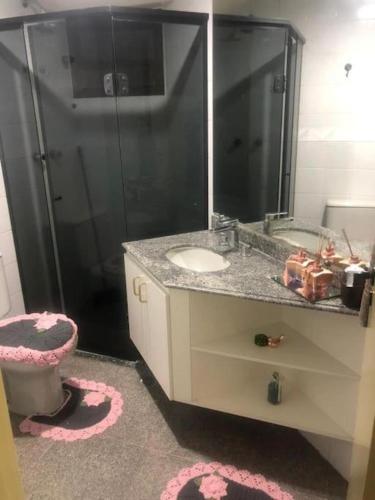 a bathroom with a toilet and a sink and a mirror at Quarto em Alphaville Barueri SP in Barueri