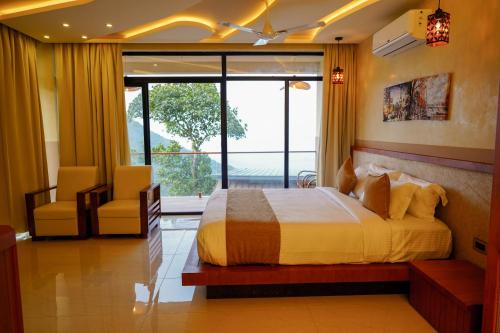 a bedroom with a bed and a chair and a window at Mount Stratus Resort Vayalada in Bālūssheri
