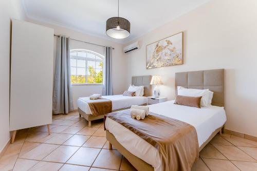 a bedroom with two beds and a window at Quinta das Laranjeiras by Algarve Holidays in Boliqueime
