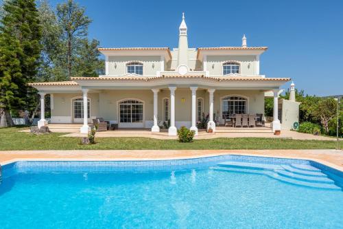 a house with a swimming pool in front of it at Quinta das Laranjeiras by Algarve Holidays in Boliqueime