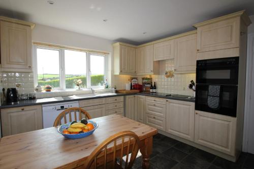 a kitchen with a wooden table with a bowl of fruit on it at Spacious seaside family house in Aberdaron with large garden and stunning sea views in Aberdaron