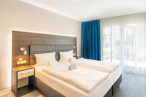 a bedroom with a large bed with a large window at SEETELHOTEL Ostseeresidenz Bansin in Bansin