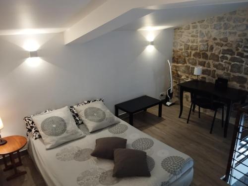 a bedroom with a bed with pillows and a table at Maison du Troubadour in Balazuc