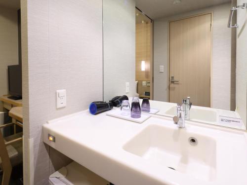 a bathroom with a sink and a mirror at Dormy Inn Gifu Ekimae in Gifu