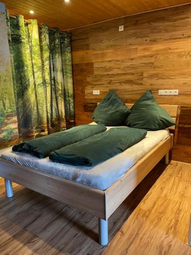 a bed with green pillows in a room with wooden walls at Farben Haus in Kail