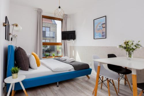 um quarto com uma cama azul e uma mesa em Palm Aparts Gdańsk em Gdansk