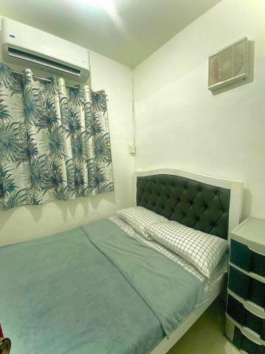 ein Schlafzimmer mit einem Bett und einem Fenster mit einem Vorhang in der Unterkunft DAVAO Transient House 2 in Davao City
